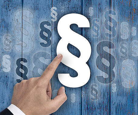 Darstellung einer Hand, die ein Paragrafenzeichen berührt