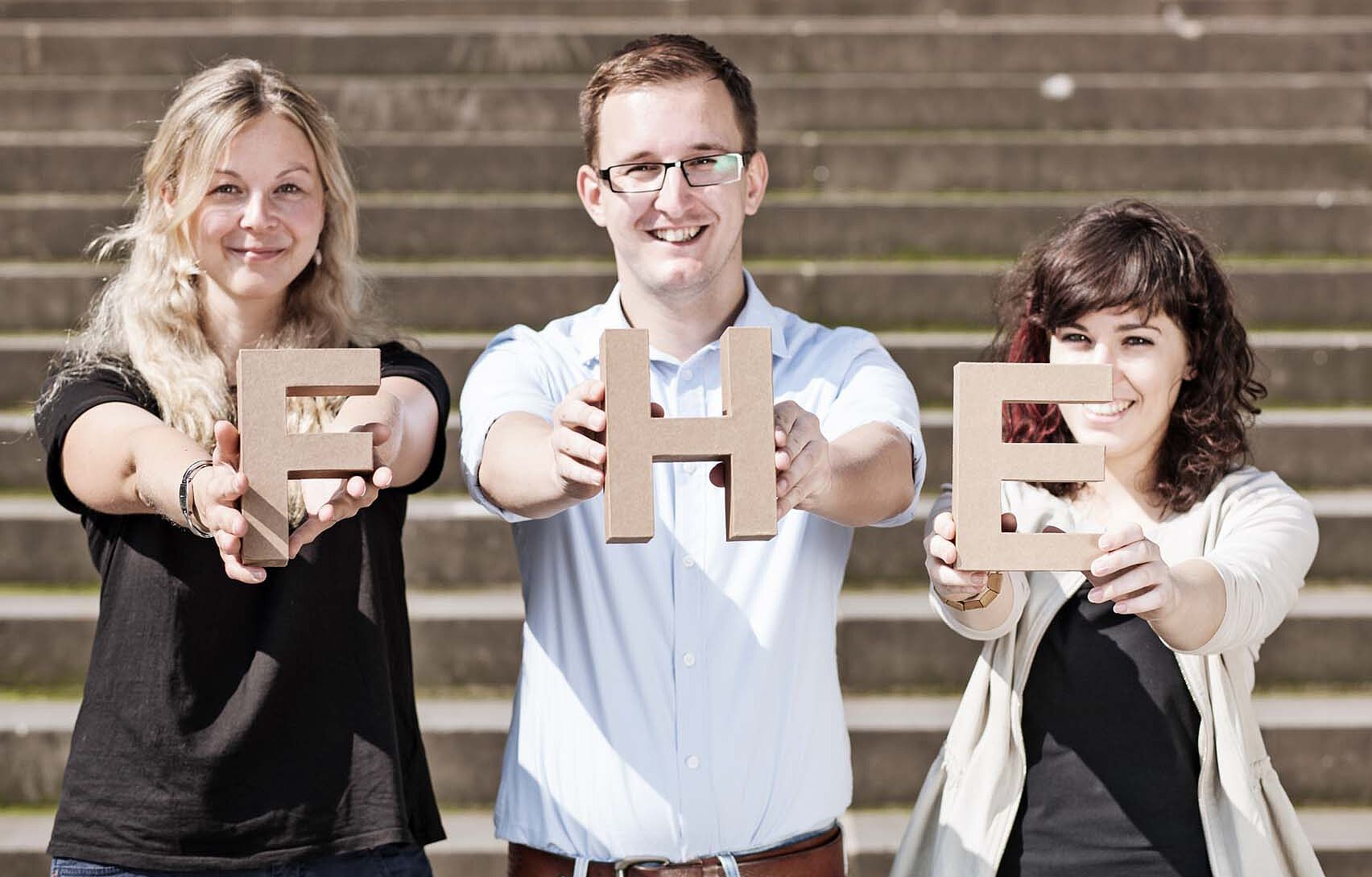 Gruppe Studierende halten FHE-Buchstaben