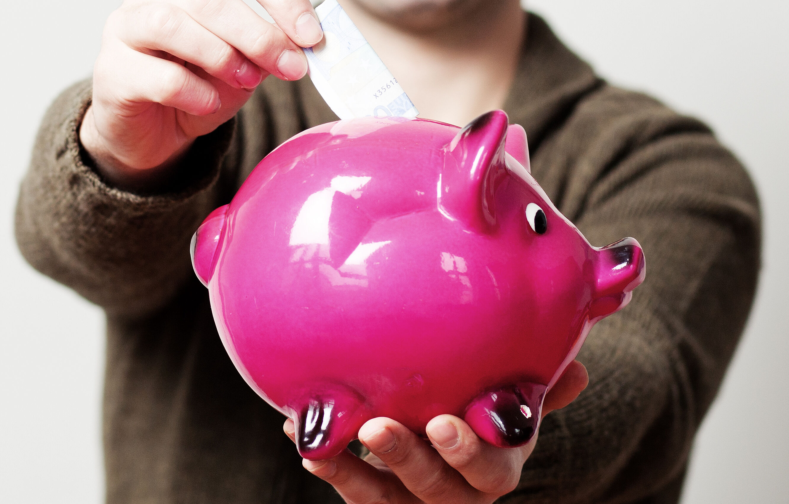 pinkes Sparschwein bekommt Geldschein