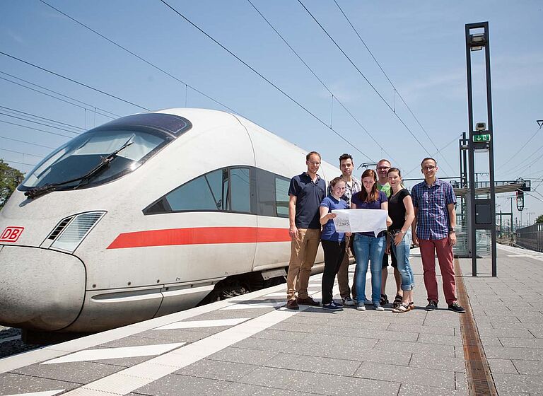 Studierende mit Professor am Bahnhof