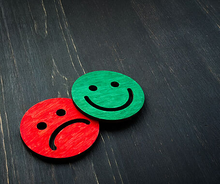 Darstellung eines grünen fröhlichen Smileys und eines roten traurigen Smileys. 