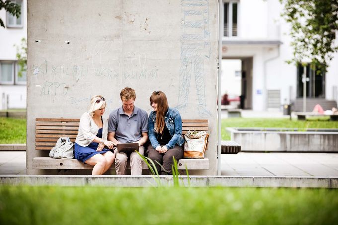Gruppe Studierende sitzen draußen am Campus
