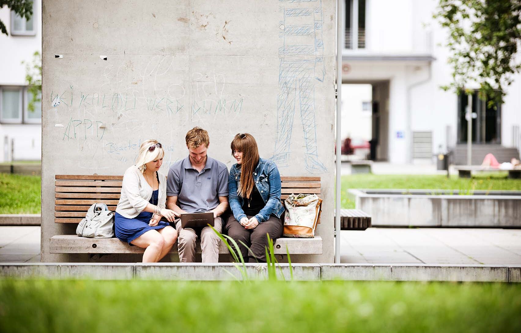 Gruppe Studierende sitzen draußen am Campus