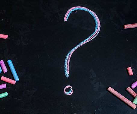 colored chalks, black blackboard with pictures question mark