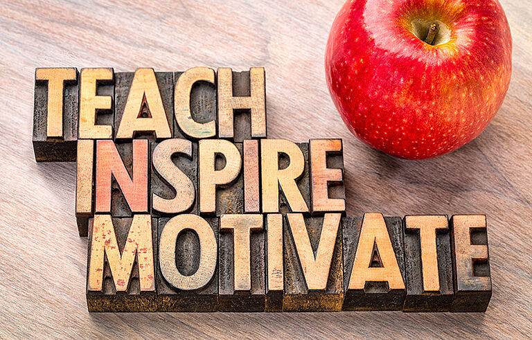 teach, inspire, motivate in Holzbuchstaben daneben ein Apfel