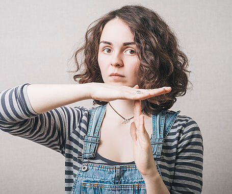 The woman has her hands stop timeout. On a gray background.
