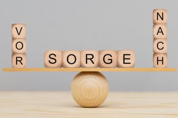 Darstellung einer ausbalancierten Wippe mit drei Holzwürfeln auf der linken Seiten, dies das Wort Vor ergeben, vier Holzwürfeln auf der rechten Seite, die das Wort Nach ergeben und in der Mitte fünf Würfeln, dies das Wort Sorge ergeben. Vorsorge ist besser als Nachsorge