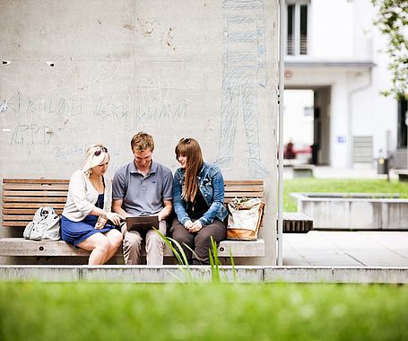 Campusleben Gruppe Studierende sitzen draußen am Campus