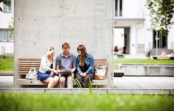 Gruppe Studierende sitzen draußen am Campus