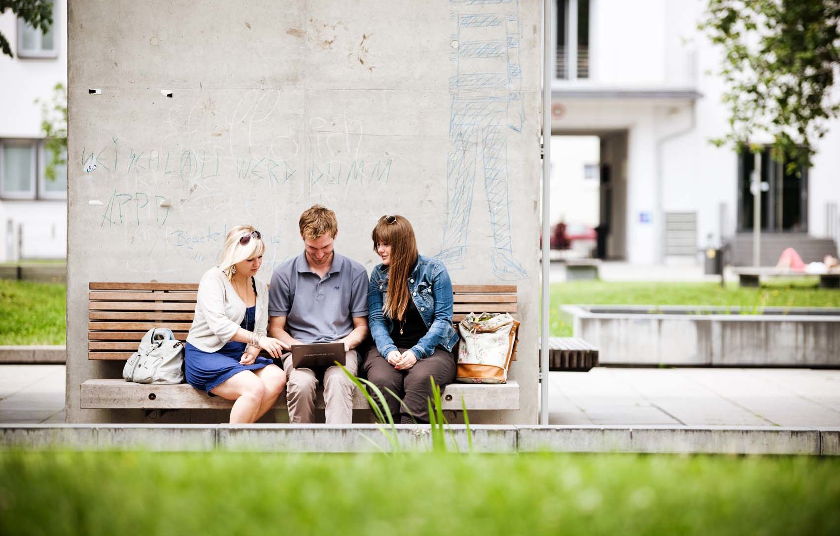 Campusleben Gruppe Studierende sitzen draußen am Campus