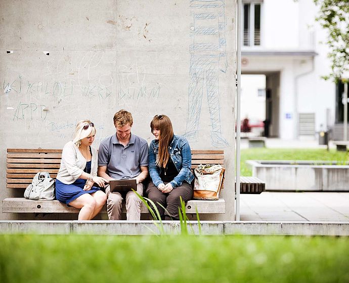 Gruppe Studierende sitzen draußen am Campus