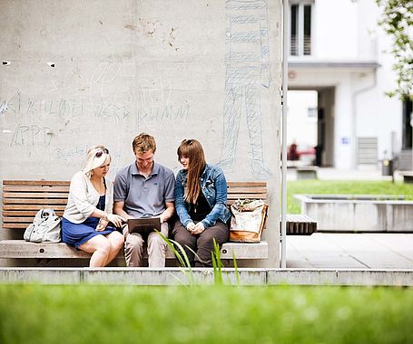 Gruppe Studierende sitzen draußen am Campus