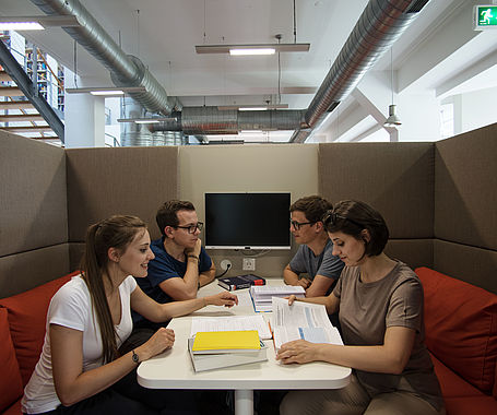 Gruppe Studierende sitzt in der Hochschulbibliothek