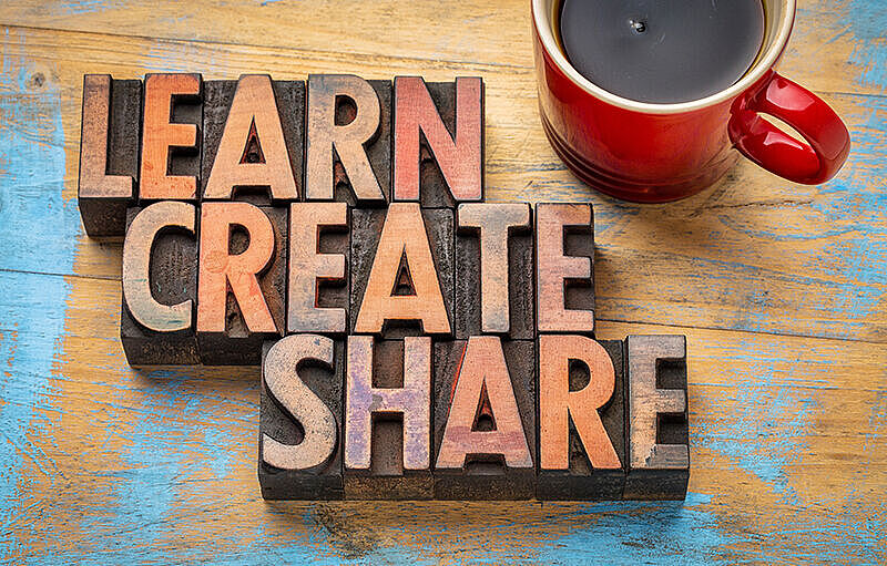 Words learn, create, share in wooden letters next to coffee cup