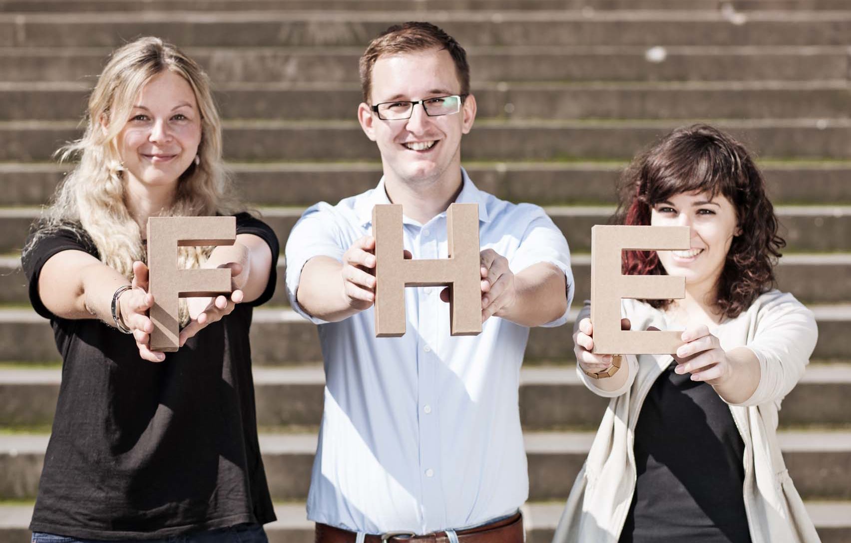 Sonstige Gruppe Studierende halten FHE-Buchstaben