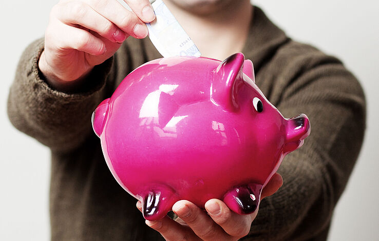 pinkes Sparschwein bekommt Geldschein