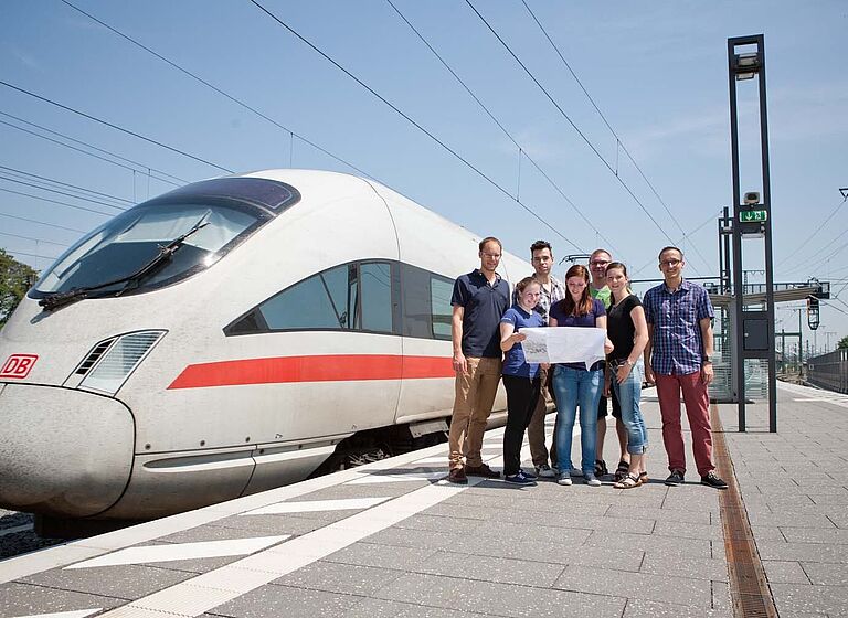 Studierende mit Professor am Bahnhof