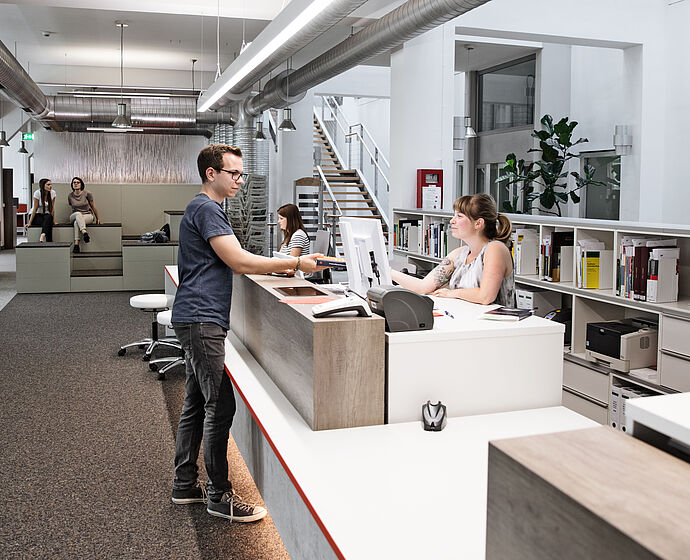 Studierender an der Theke in der Bibliothek