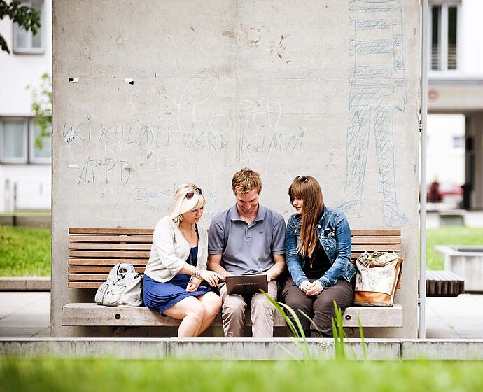 Gruppe Studierende sitzen draußen am Campus