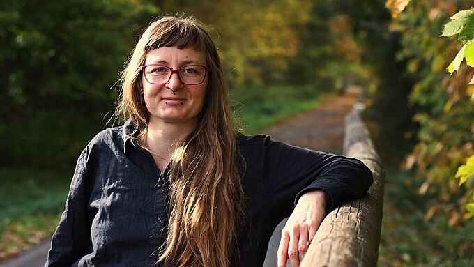 Junge Frau mit langen Haaren und Brille an Geländer gelehnt