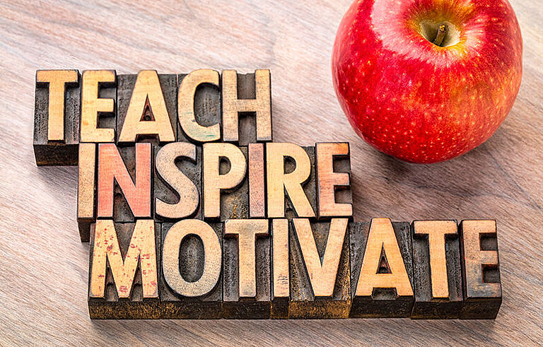 teach, inspire, motivate in Holzbuchstaben daneben ein Apfel