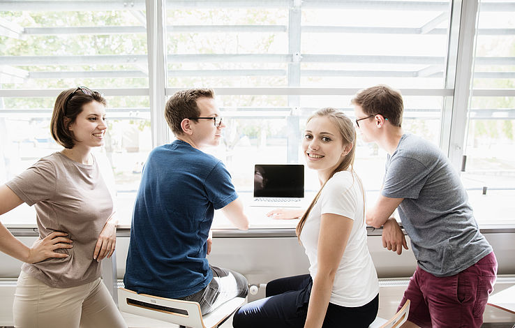 Gruppe Studierende sitzt in der Hochschulbibliothek