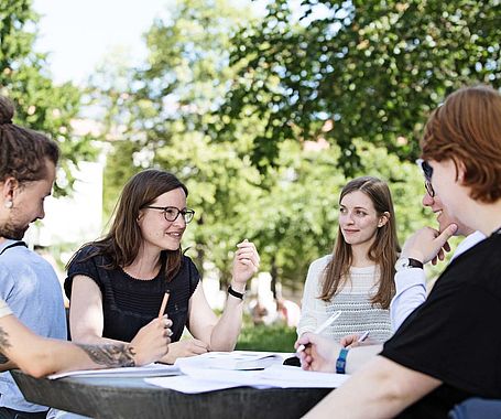 Gruppe Studierender sitzt auf dem Campus