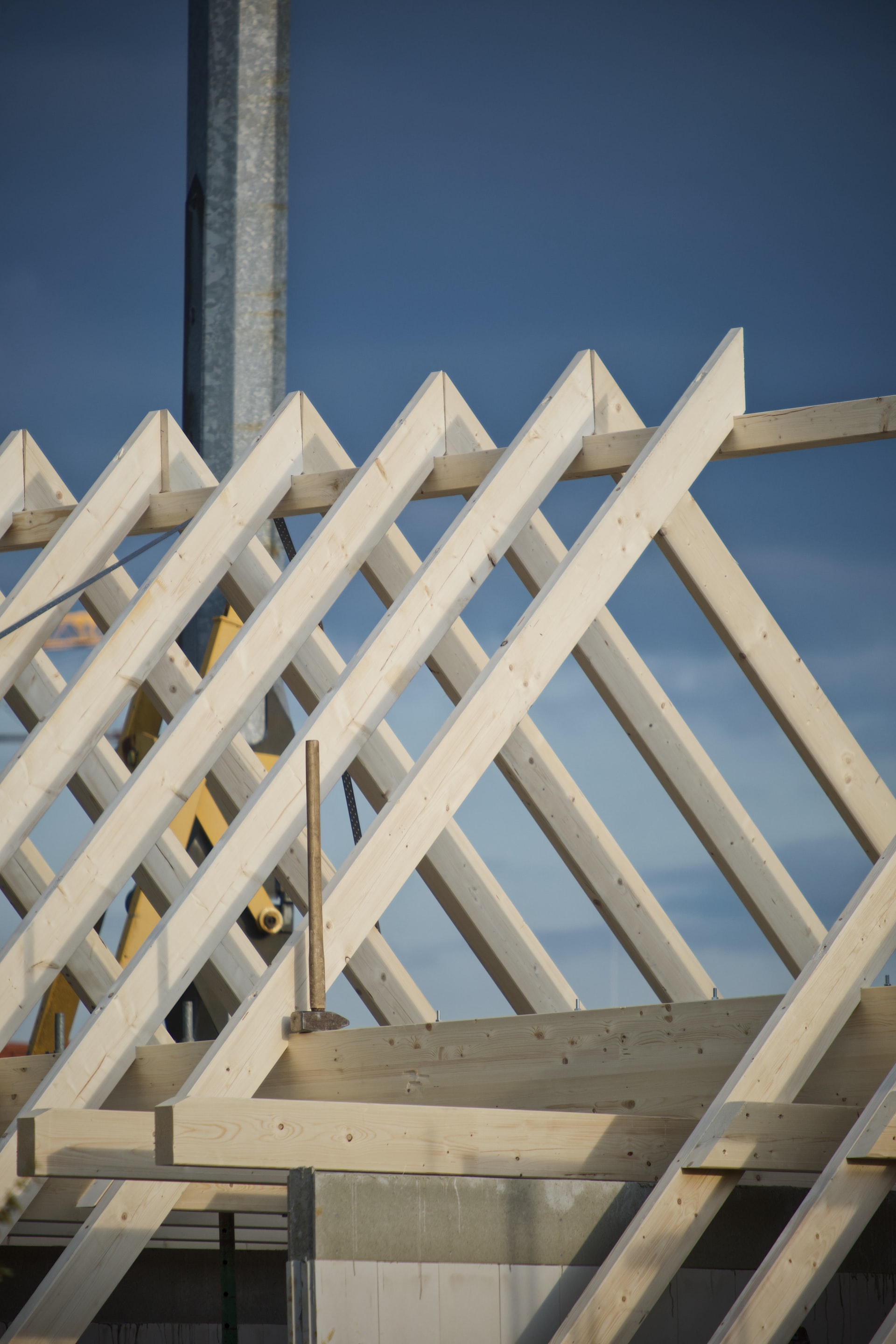 Ein Dachstuhl mit Holzbalken in Nahaufnahme, blauer Himmel